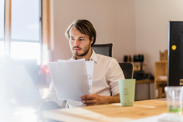 Businessman reading document at desk in office