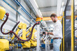 © tunedin - Side view of confident robotics expert examining machinery in factory