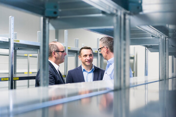 Wall Mural - Three businessmen having a discussion in a factory storehouse