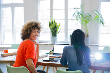 Poster - Smiling woman with colleague in modern office with video projector on table