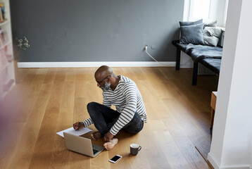 Poster - Mature man sitting on floor, working on laptop