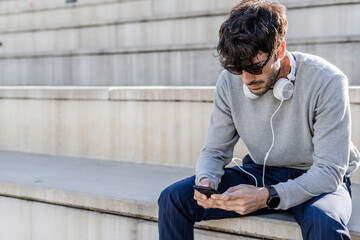 Sticker - Man sitting on outdoor stairs using smartphone