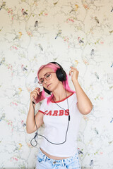 Sticker - Enthusiastic young woman with pink hair listening to music at home