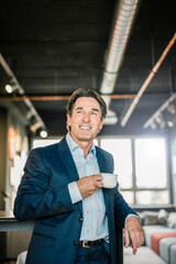 Poster - Smiling businessman in office with cup of coffee