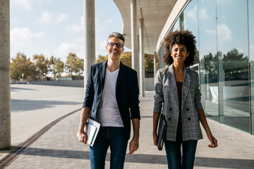 Wall Mural - Portrait of two happy colleagues outside office building