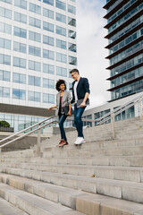 Two colleagues walking and talking on stairs outside office building in the city