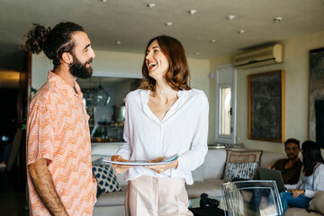 Poster - Happy man and woman talking with friends sitting on couch in background