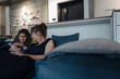© tunedin - Happy woman and girl sitting on couch in office using smartphone