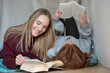 © tunedin - Two friends lying side by side on the floor reading books
