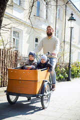 Sticker - Happy father with two children riding cargo bike in the city