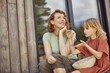 © tunedin - Smiling mother talking with daughter while sitting outside tiny house