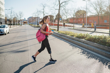 Wall Mural - Sporty young woman with leg prosthesis walking in the city