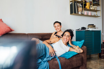 Wall Mural - Smiling lesbian couple watching TV on sofa