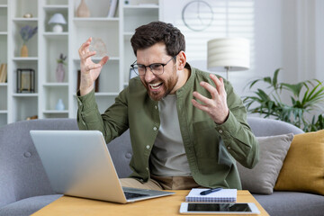 Wall Mural - Man experiencing frustration and anger while working from home, struggling with laptop. Home office setting, emotional stress, and technical issues.