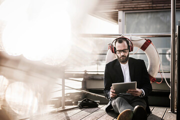 Sticker - Hip businessman working on a houseboat, using headphones and digital tablet