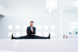 © tunedin - Smiling businessman doing the splits on reception desk in office