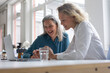 © tunedin - Two happy businesswomen using laptop at desk in office together