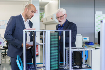 Senior male manager discussing over machinery with colleague at factory