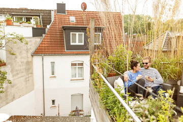 Wall Mural - Young couple relaxing on their balcony, sitting on couch