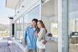 © tunedin - Happy couple standing at luxury beach house