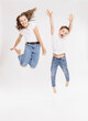© tunedin - Cheerful siblings jumping against white background