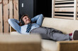 © tunedin - Businessman with headphones lying on couch in office lounge
