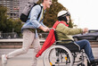 © tunedin - Young man pushing senior man sitting in a wheelchair dressed up as superhero
