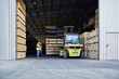 © tunedin - Two workers standing in factory warehouse next to forklift