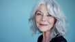 © Diflope - stunning beautiful and self confident best aged woman with grey hair smiling into camera on light blue background