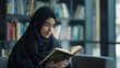 © Maksym - A modern Muslim woman in hijab, reflecting on her faith while reading the Quran in a sleek, well-lit study area.