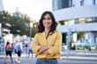 © Stock 4 You - Smiling portrait of middle eastern Israel girl with crossed arms at busy city urban street. Young Arabian Indian woman, businesswoman, business freelancer in casual shirt looking camera. Copy space