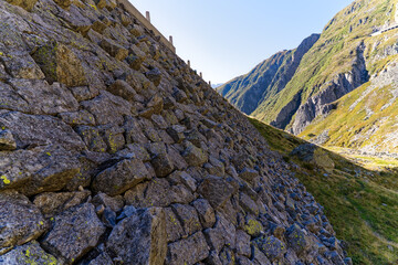 Wall Mural - Scenic view of retaining stone wall of historic mountain pass road named Tremola at Swiss Gotthard Pass on a sunny late summer morning. Photo taken September 10th, 2023, Gotthard, Switzerland.