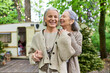 © Bliss - Two middle-aged women, a lesbian couple, share a laugh while camping in a lush green forest. A camper van is visible in the background.
