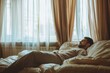 © artemstepanov - Young man relaxes at cozy home on couch by window. Happy man resting on sofa near window