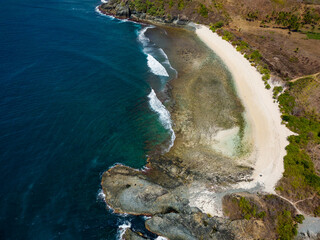 Wall Mural - Aerial view of a small, empty tropical beach surrounded by blue ocean (Semeti Beach, Lombok)