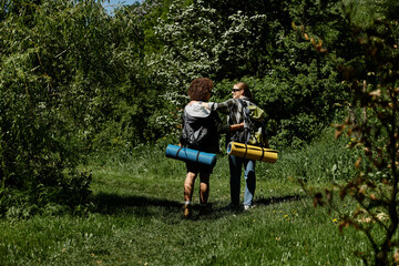 Wall Mural - Two young women, a lesbian couple, hike together through a lush green forest.