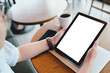 © Thaspol - Person Holding Tablet with Blank Screen at Café Table with Coffee and Smartphone