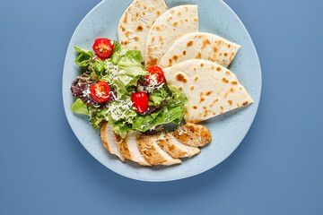 Wall Mural - Delicious Caesar Salad with Grilled Chicken and Tortilla Bread on Blue Plate