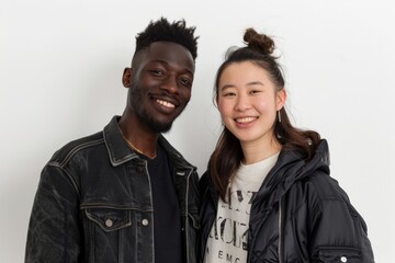 Wall Mural - Portrait of a grinning multicultural couple in their 30s wearing a trendy bomber jacket in white background