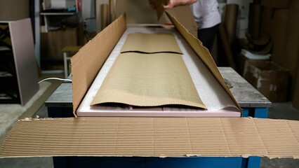 A man packs furniture products in cardboard packaging. Furniture manufacture. Packing furniture in a cardboard box at the factory.