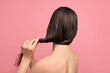 © New Africa - Woman applying hair mask on pink background