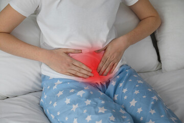 Poster - Woman suffering from abdominal pain on bed, closeup