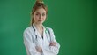 © Netroder - A female doctor with arms crossed, wearing a white coat and stethoscope, smiling confidently against a green background.