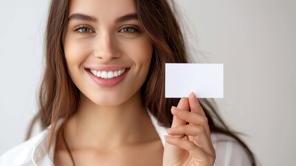 Business card. Casual young and attractive businesswoman showing her blank white business card / empty sign. Mixed race model isolated on seamless white background.