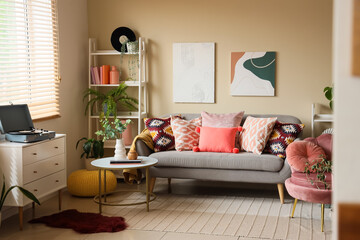 Wall Mural - Interior of living room with cozy sofa, pillows, pictures and coffee table