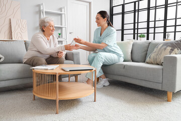 Poster - Senior woman taking bottle of water from physical therapist at home