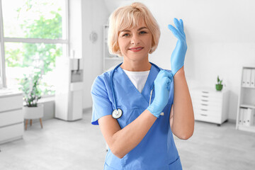 Wall Mural - Female doctor putting on medical gloves at hospital