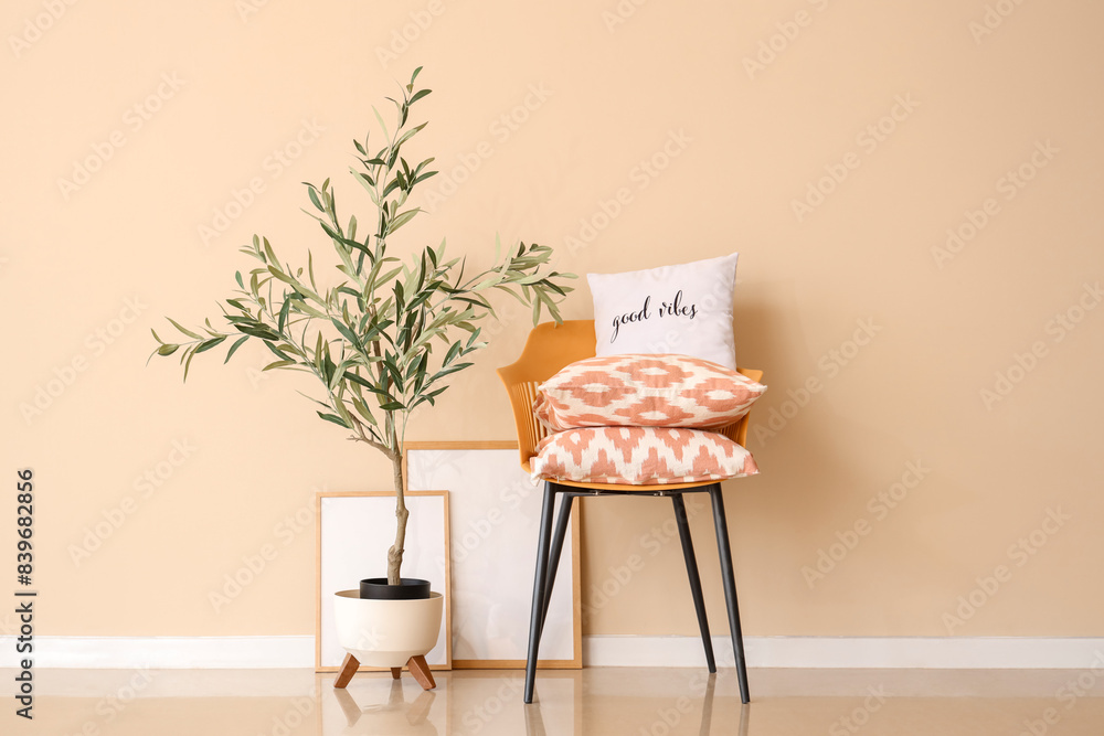 Chair with stack of soft pillows and olive tree in living room