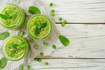 Poster - Green pea soup with mint in jars on a white wooden surface