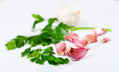 Wall Mural - Cutting board with fresh seasonings on a wooden background. White garlic heads and cloves and parsley leaves. Condiments